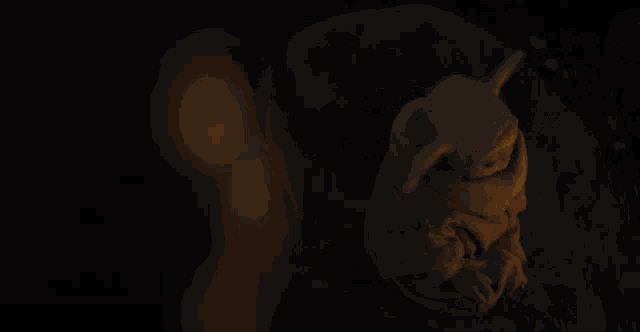 a baby yoda is sitting in the dark with a light behind him