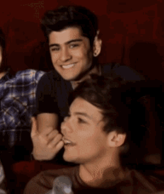 a man is giving a thumbs up while sitting next to another man