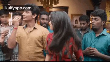 a group of people are standing around a woman dancing in a room .
