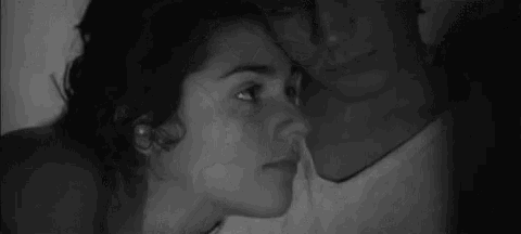 a man and a woman are kissing each other in a black and white photo .