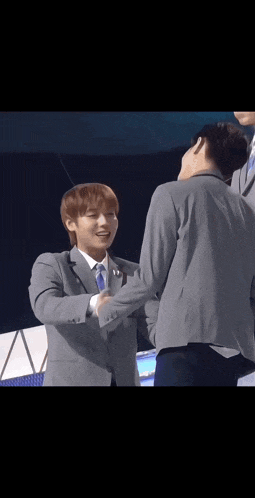 a man in a suit and tie is shaking hands with another man