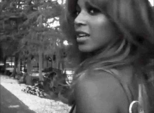 a black and white photo of a woman walking down a sidewalk