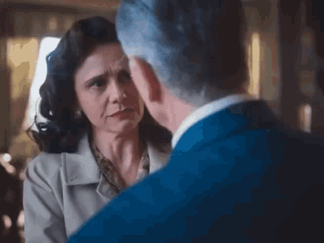 a man in a blue suit is hugging a woman in a trench coat .