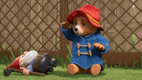 a teddy bear is standing next to a gnome with a red hat