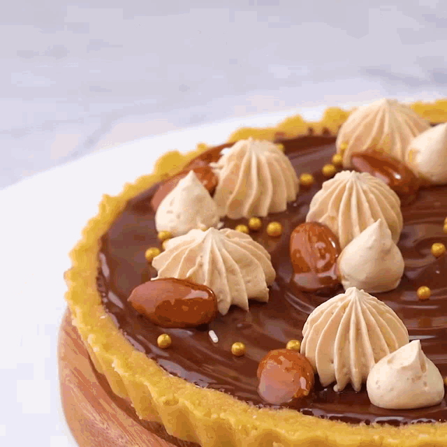 a close up of a chocolate cake with whipped cream and nuts on top