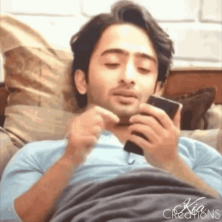 a man laying on a bed looking at a cell phone