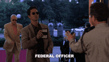 a man in a suit holding a wallet with the word federal officer on it