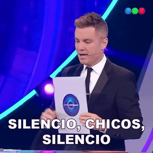 a man in a suit and tie holds a piece of paper that says silencio
