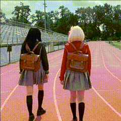 two girls walking down a track with backpacks on