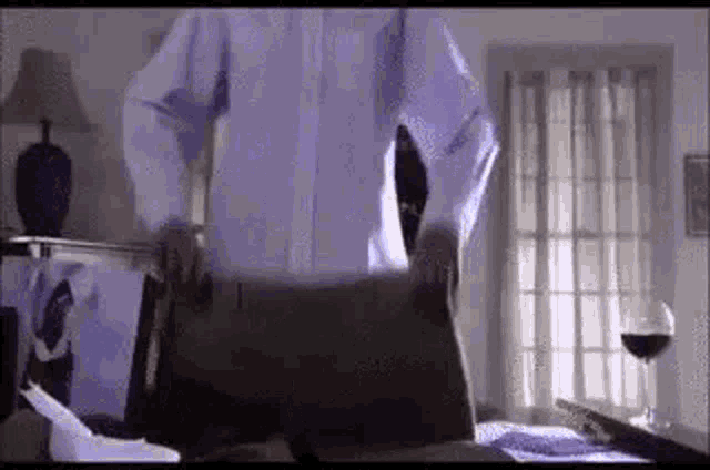 a man in a white shirt and tie is standing in a bedroom with a briefcase .