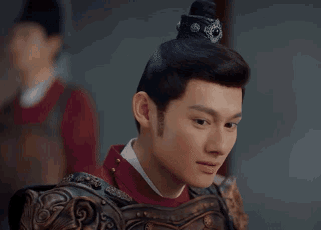 a close up of a man wearing armor and a red shirt