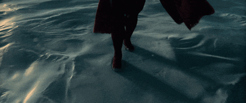 a person in a red cape walking on a snowy surface