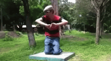 a man in a red shirt and hat is kneeling down in the grass