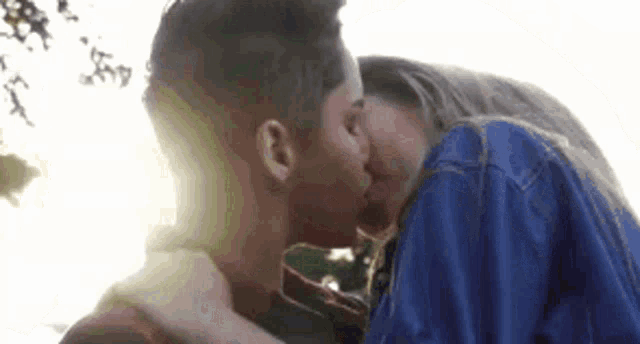 a man and a woman are kissing each other in front of a tree .