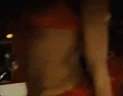 a blurry picture of a man in a red jacket talking on a cell phone .