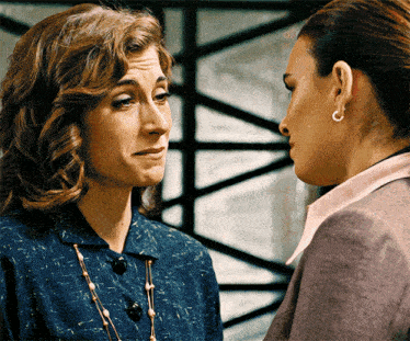 two women are looking at each other and one is wearing earrings