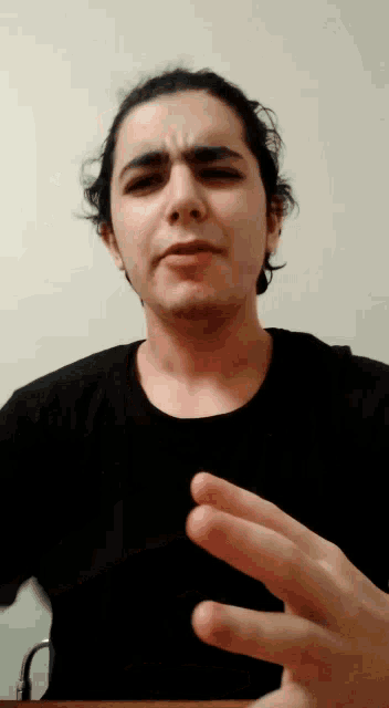 a man in a black shirt is making a gesture with his hands