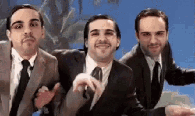 three men in suits and ties are dancing together in front of a blue background .