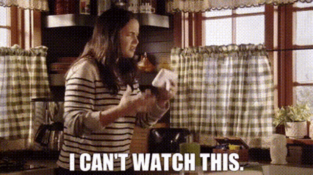 a woman is standing in a kitchen holding a bottle and saying `` i can t watch this . ''