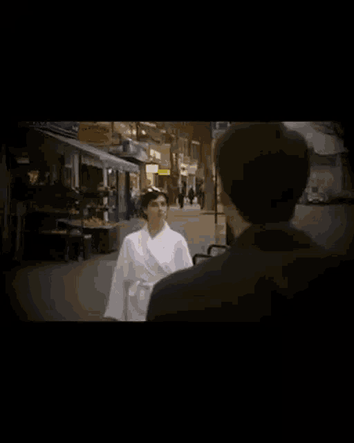a man and a woman are walking down a street in front of a store that says ' abercrombie ' on it