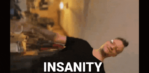 a man in a black shirt is dancing in a room with the word insanity written on the screen .