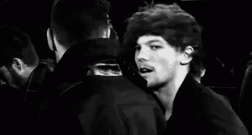 a black and white photo of a man kissing another man in a crowd of people .
