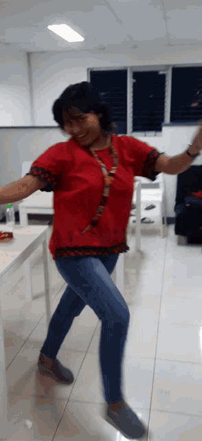 a woman wearing a red shirt and blue jeans is dancing