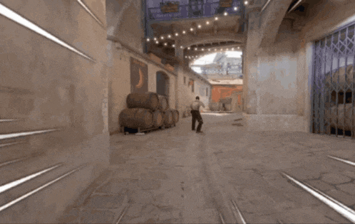a man walking down a street with barrels stacked on the side
