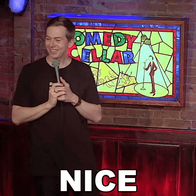 a man is holding a microphone in front of a sign that says comedy cellar