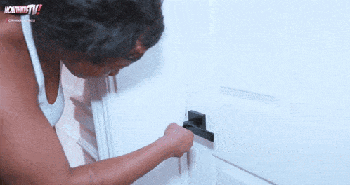 a woman opens a door with a monitor tv logo in the corner