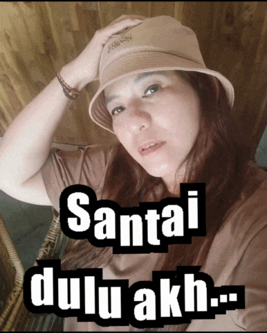 a woman wearing a hat with the words santai dulu akh written on it