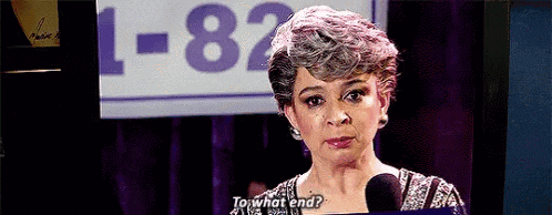 a woman is talking into a microphone in front of a sign that says `` to what end '' .