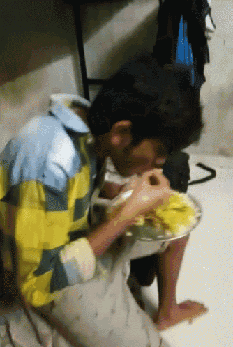 a man in a yellow and blue shirt is eating food
