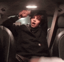 a person is sitting in the back seat of a car with their mouth open .