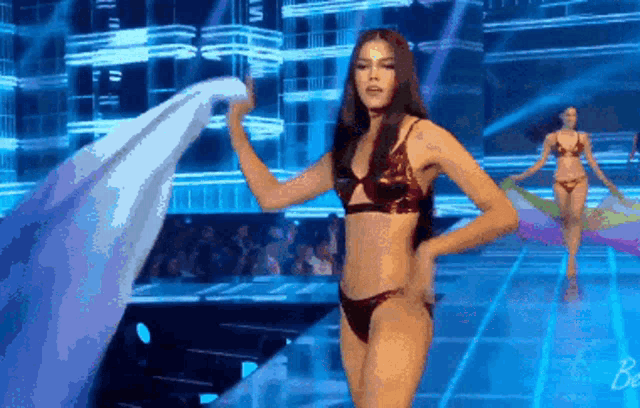 a woman in a bikini is walking down a runway .