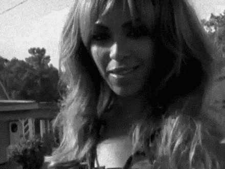 a black and white photo of a woman with long hair smiling and looking at the camera .