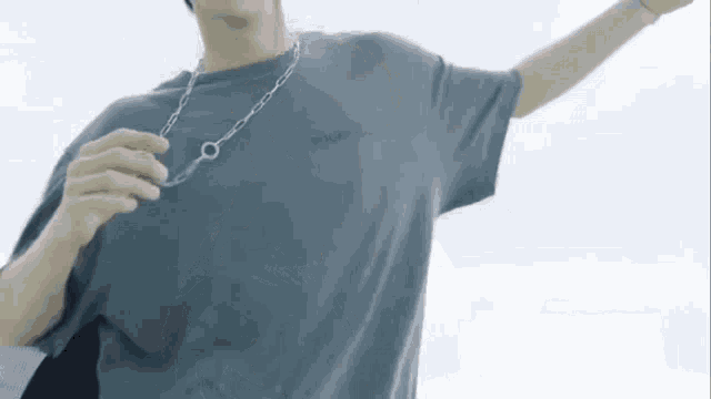 a man wearing a gray t-shirt and a silver chain around his neck