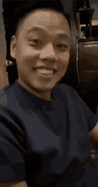 a man wearing a blue shirt is smiling and looking at the camera