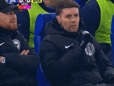 a man drinking water from a bottle while watching a sports game
