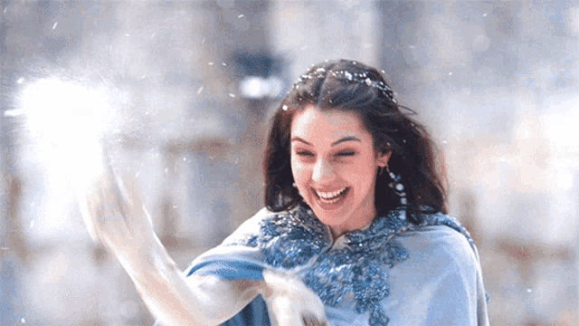 a woman in a blue cape is playing in the snow