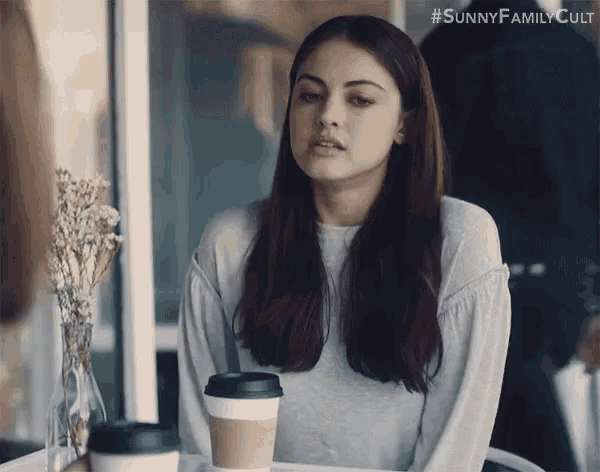 a woman is sitting at a table with a cup of coffee and the hashtag #sunnyfamilycult