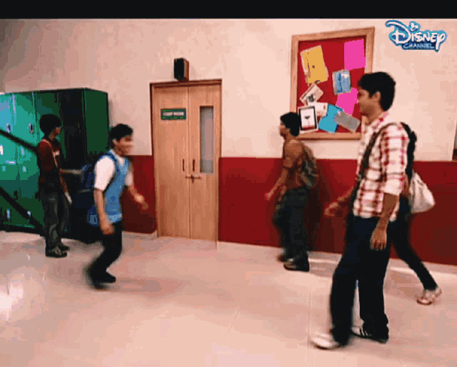 a group of people walking in a hallway with a disney logo on the bottom right