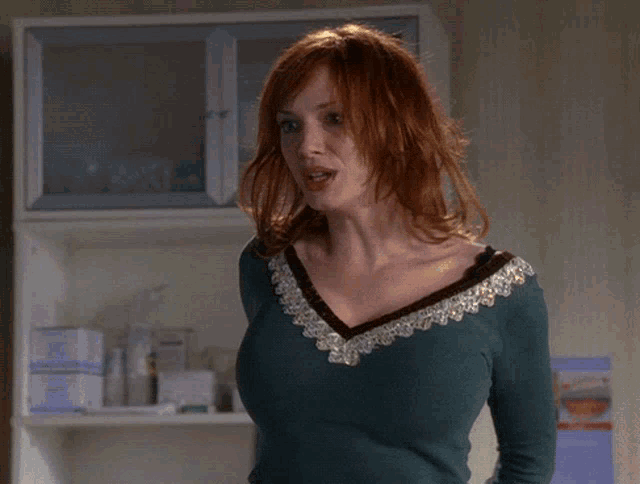 a woman with red hair and a green top smiles