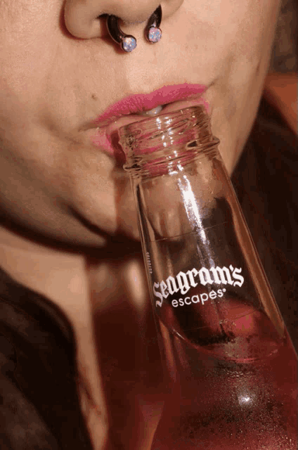 a woman is drinking from a bottle that says seagram 's escapes