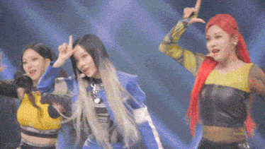 a group of three women are dancing on a stage and one of them has red hair .