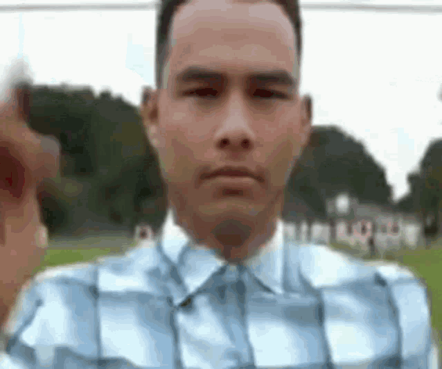 a man in a plaid shirt is giving the middle finger in a blurry photo .