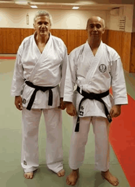 two men in white karate uniforms with black belts