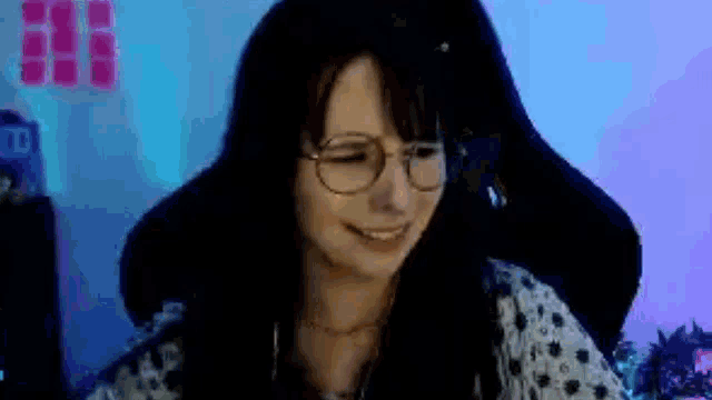 a woman wearing glasses is smiling while sitting in a chair in front of a computer .