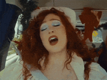 a woman with red hair and blue eye shadow is singing