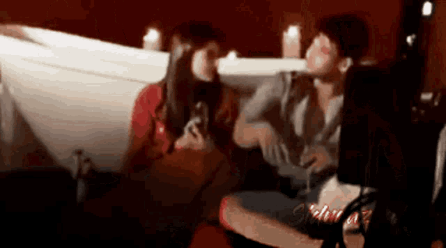 a man and a woman are sitting on a couch in a dark room .